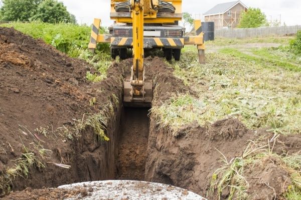 An excavator digging a drainage trench in open ground