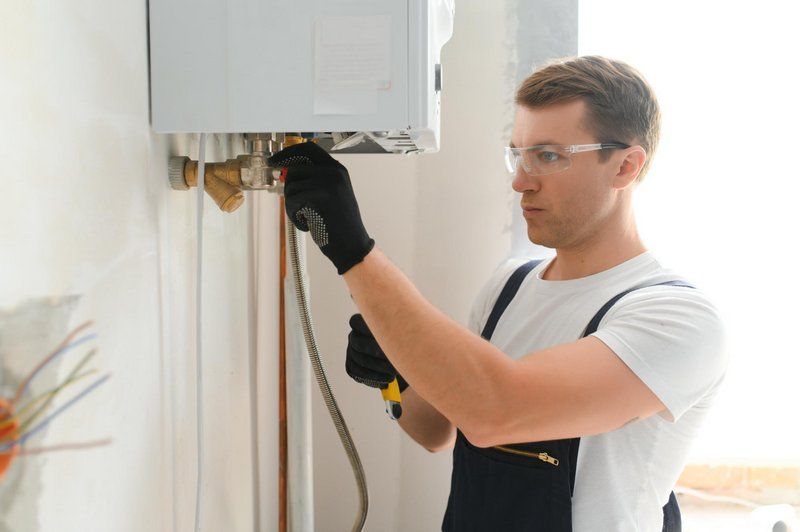A plumber connecting pipework on a newly installed water heater